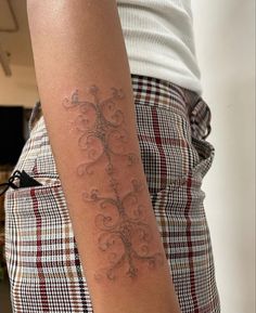 a woman's arm with a tattoo on it that looks like an ornamental tree