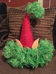 a red and green christmas tree decoration sitting on top of a brown couch next to pillows