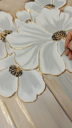 a person is painting flowers on a piece of wood with gold foil and acrylic paint