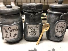 three jars with words on them sitting next to each other and a wooden spoon in the middle