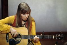 a woman with long hair is playing an acoustic guitar