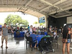 people are standing and sitting at tables in an open area