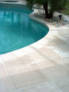 an empty swimming pool in the middle of a backyard with palm trees and landscaping around it