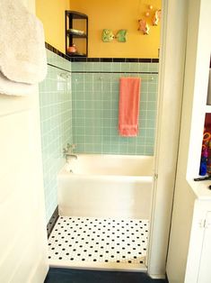 a bathroom with yellow walls and black and white flooring, including a bathtub