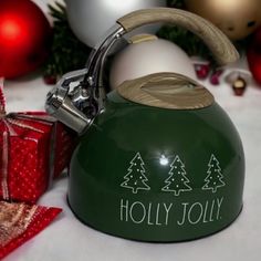 a green tea kettle sitting on top of a table next to christmas decorations and presents