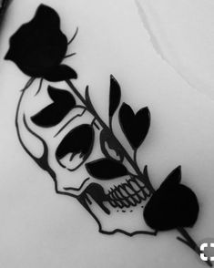 a black and white photo of a skull with flowers on it's head, next to two markers