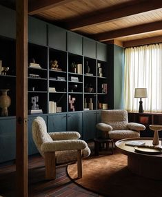 a living room with two chairs and a coffee table in front of bookshelves