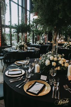 the table is set with black linens and white flowers, candles, and place settings