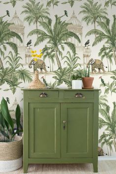 a green cabinet in front of a wallpaper with dinosaurs and palm trees on it