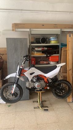 a dirt bike is parked in front of a storage area with boxes and other items