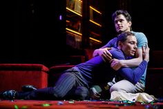 two men hugging each other on stage in front of a red couch and dark background