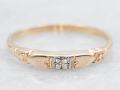 a gold wedding ring with two diamonds on the side and an arrow in the middle