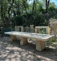 a stone bench sitting in the middle of a forest next to two cement urns