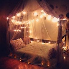 a canopy bed with fairy lights on it