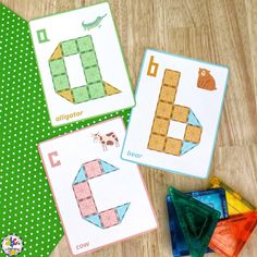 three matching cards with letters and numbers are on the floor next to some colored blocks