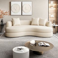 a modern living room with white furniture and art on the wall behind the couches