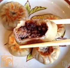 three small dumplings on a plate with chopsticks sticking out of the top