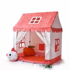 a pink and white doll house with a cat on the floor