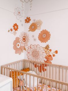 a baby's crib with flowers painted on the wall and in front of it