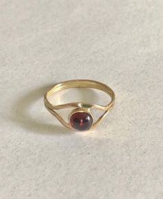 This 14 K gold ring features a 6 mm. garnet a very popular stone. The  splitter band gives to the ring a nice looking and is very comfortable. Yellow Gold Garnet Rings, Classic Garnet Rings With Round Cut, Classic Garnet Round Cut Ring, Classic Garnet Ring With Round Cut, Yellow Gold Garnet Rings With Round Cut, Classic Round Garnet Ring, Formal Garnet Ring With Polished Finish, Promise Ring With Hallmarked Garnet Birthstone, Classic Yellow Gold Garnet Rings