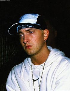 a young man wearing a white hoodie and a chain around his neck is staring at the camera