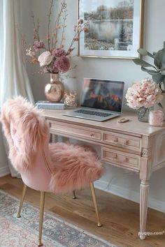 a desk with a laptop and pink chair in front of it, along with flowers