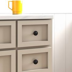 a yellow cup sitting on top of a white cabinet