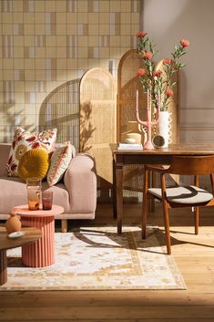 a living room filled with furniture and flowers on top of a wooden table in front of a wall