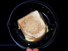 a grilled cheese sandwich in a cast iron skillet with an orange heart on the side