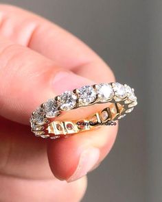 a person holding a gold ring with white stones on it's side and the middle section