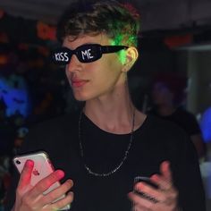 a young man wearing sunglasses and holding a cell phone in his hand with the word kiss me on it