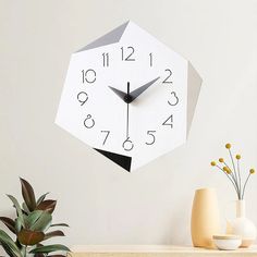 a clock that is on the side of a wall next to some plants and vases