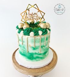 a birthday cake with green icing and gold decorations