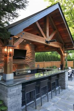 an outdoor kitchen with grill and bar stools