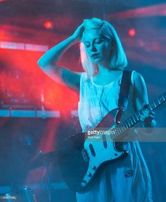 a woman holding a guitar while standing on stage