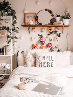 a bed with white sheets and pink flowers on the headboard next to a laptop