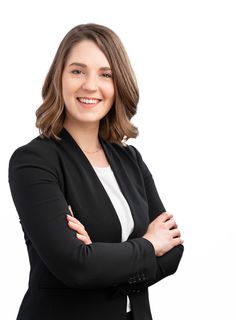 a woman with her arms crossed smiling at the camera while wearing a black blazer and white shirt