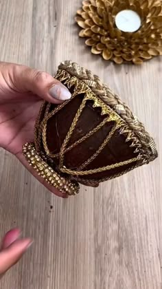 a hand holding a chocolate cake on top of a wooden table next to a candle