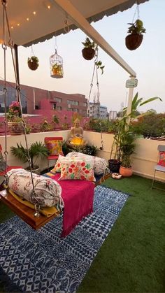 an outdoor living area with hanging plants and couches on the roof top deck at dusk