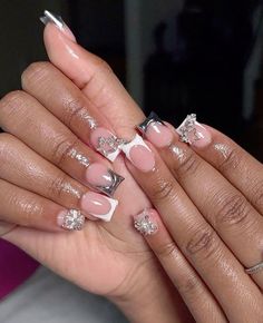 a woman's hands with pink and white nail polishes on their nails, holding onto her manicures