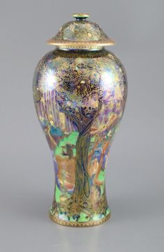 a colorful vase with a tree painted on the front and bottom, sitting against a gray background