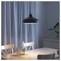 a dining room table with two chairs and a light hanging over it's head