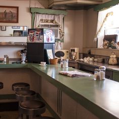 an empty restaurant with green counter tops and stools in front of the bar area