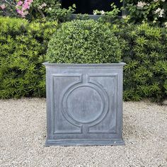 a grey planter sitting on top of a gravel ground