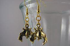 Two gold pewter bat charms dangle from gold-plated jump rings and earring hooks, creating a sophisticated bat-loving fashion statement. Gold-plated bat charms Gold-plated components 1.5 inches long X 0.75 inches wide (4 cm long X 1.8 cm wide) Bat Earrings, Girl Jewelry, Jump Rings, Fashion Statement, Bat, Gold Earrings, Piercings, Jewelry Accessories, Gold Necklace