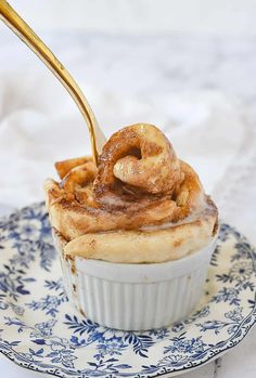 a cupcake on a blue and white plate with a golden spoon sticking out of it