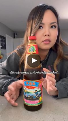 a woman is holding a bottle of hot sauce