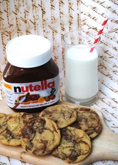 chocolate chip cookies and nutella spread on a wooden board with a glass of milk