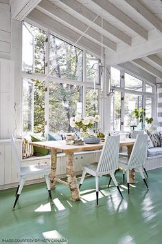 a dining room with green flooring and white furniture in the center is a window seat that seats four people