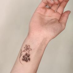 a woman's hand with a small flower tattoo on her left wrist and the other arm